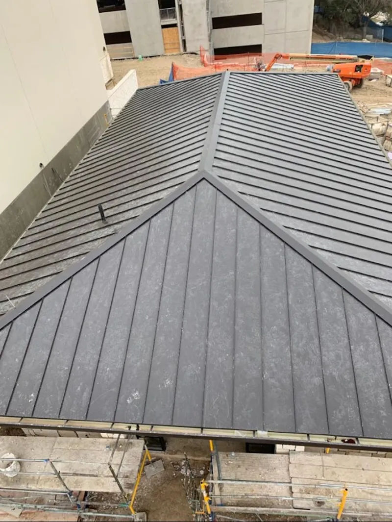 Commercial metal roof construction with crane equipment in Grove